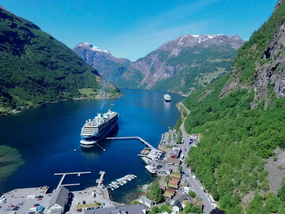 Aerial view of cruise ship anchored in narrow deep blue fjord