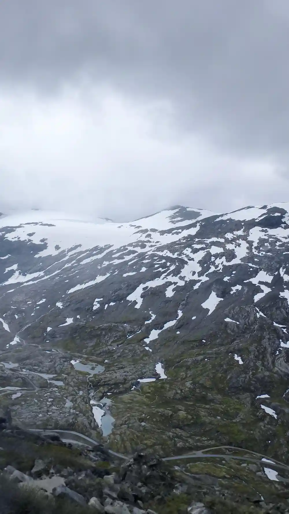 Aerial view of mountain road and scattered snow patches