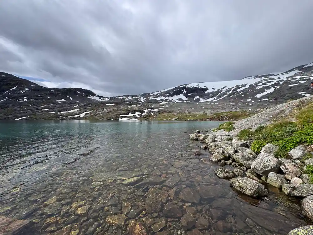 Alpine lake surrounded by snow-capped mountains and rocks
