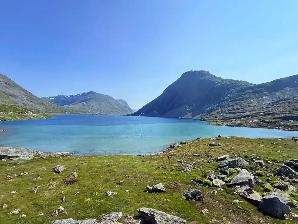 Bright blue alpine lake with rocky shore and mountains