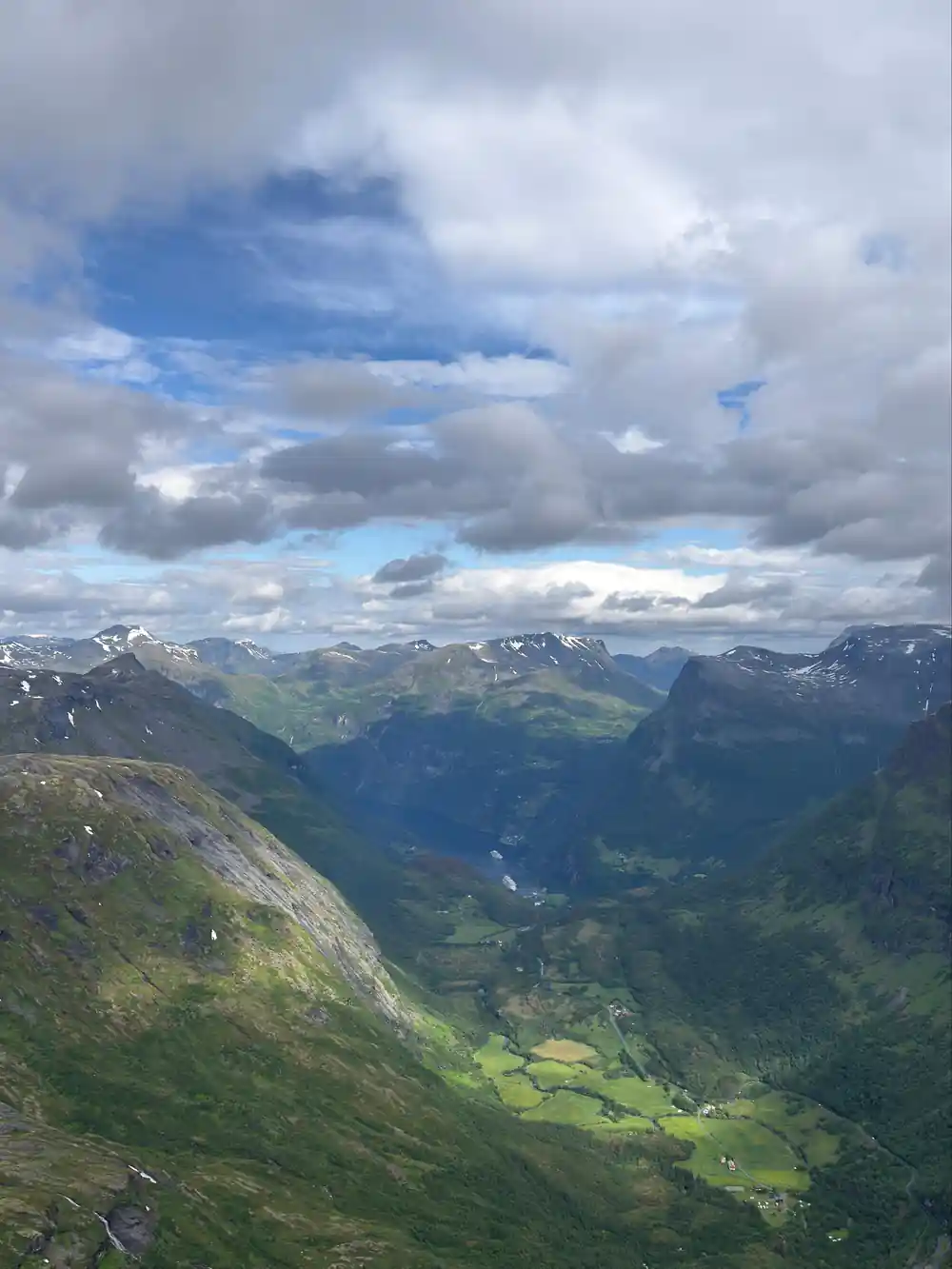 Broad valley between steep green mountains under clouds