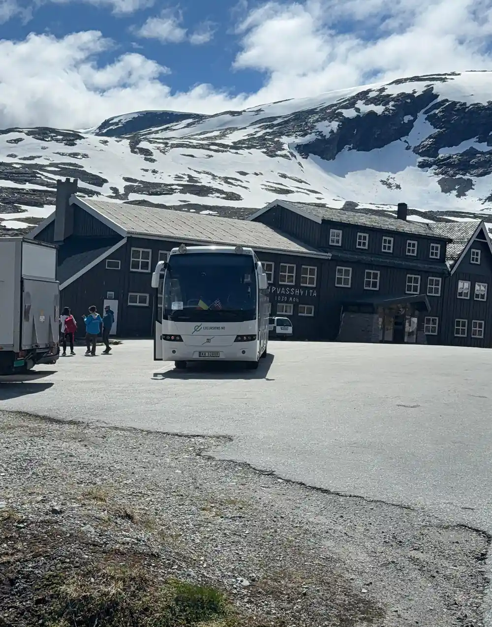 Coach bus parked at mountain lodge with snowy peaks behind