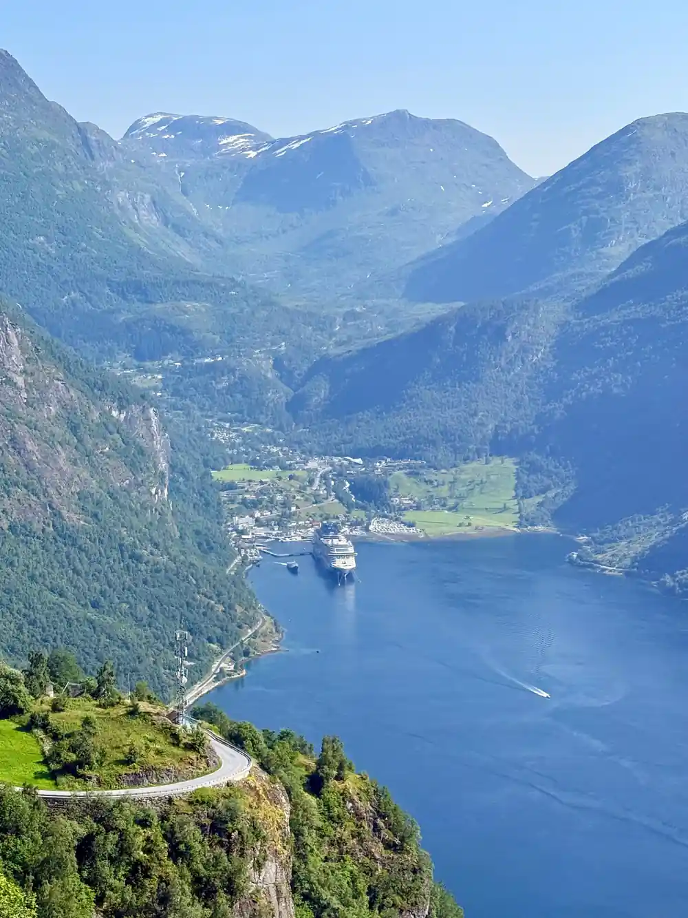 Cruise ship in blue fjord surrounded by steep mountains