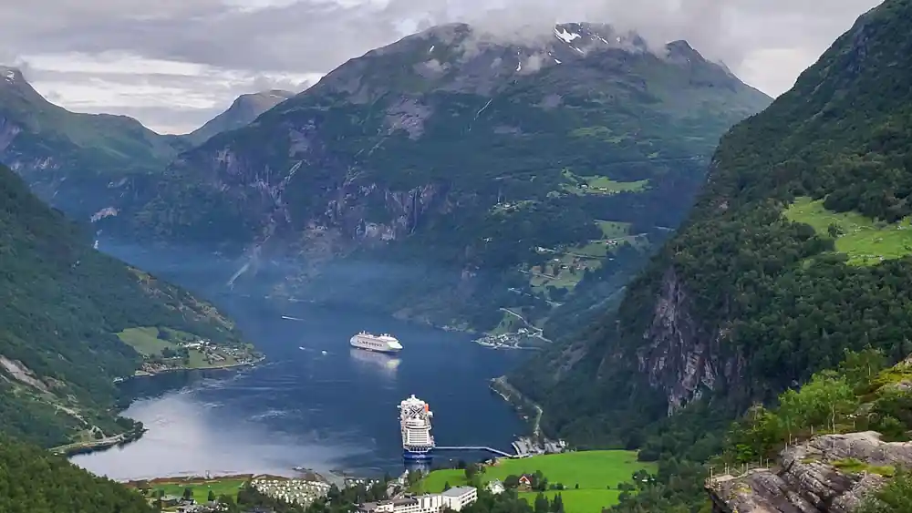 Cruise ships on fjord surrounded by steep green mountains