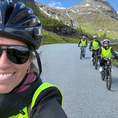 Cyclists in hi-vis vests riding down a mountain road