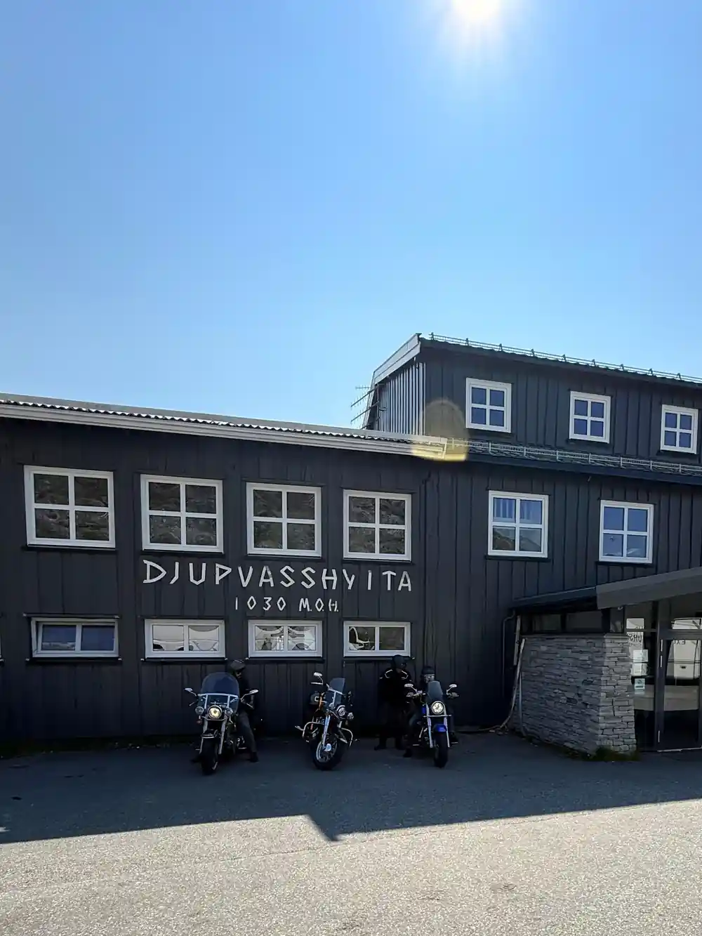 Dark wooden building with motorcycle parking and sign