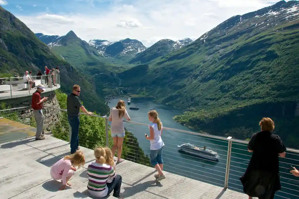Elevated viewing platform with tourists overlooking green fjord valley