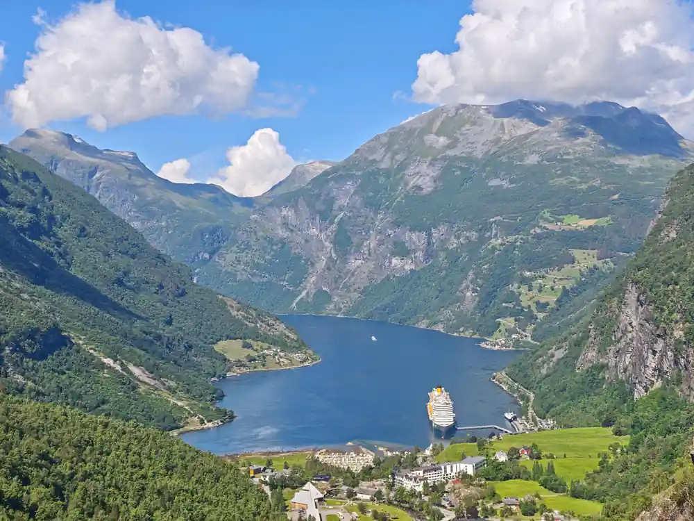 Fjord with cruise ship, surrounded by steep green mountains