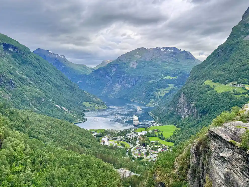 Fjord valley with village and cruise ship between green mountains