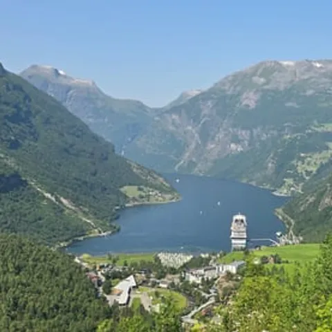 Green Geiranger valley with a cruise ship on the fjord