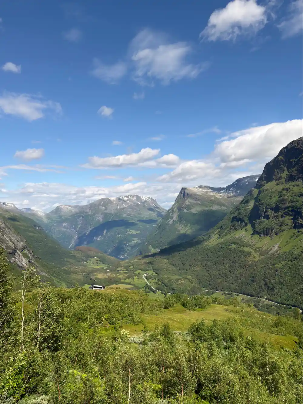 Green forested valley between steep mountains under blue sky