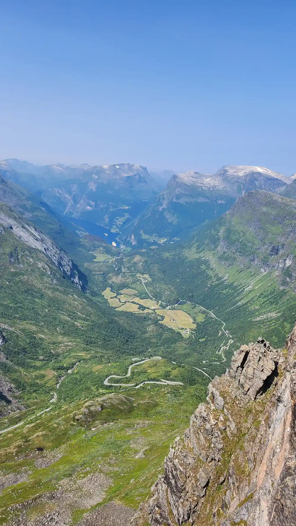 Green valley with winding road viewed from cliff edge