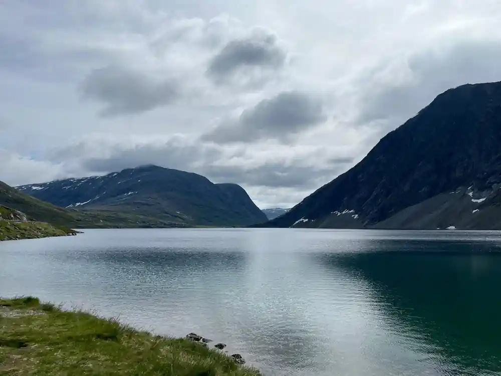Long fjord lake with mountains under cloudy sky