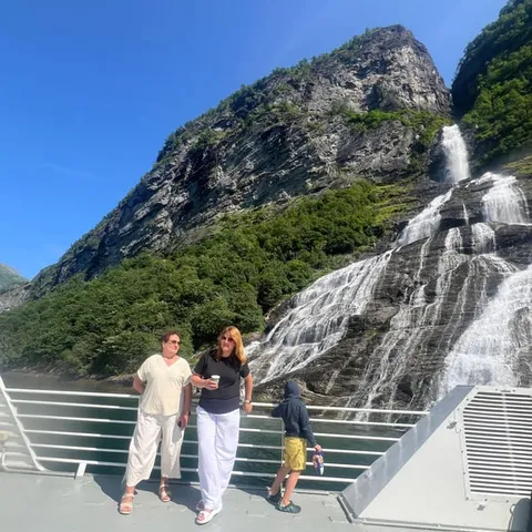 Passengers on a boat deck beside a waterfall