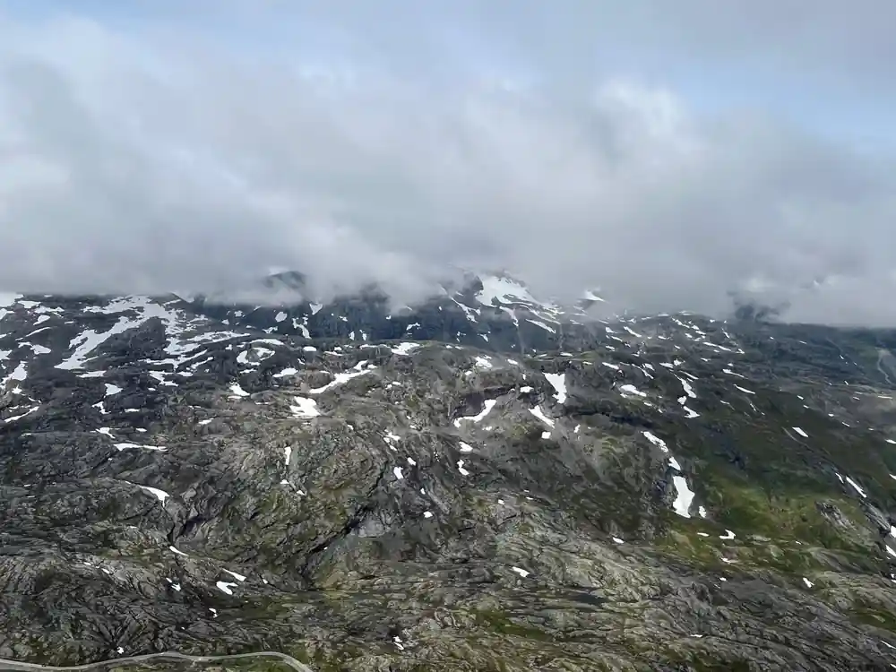 Rocky mountain slope with sparse vegetation and snow patches