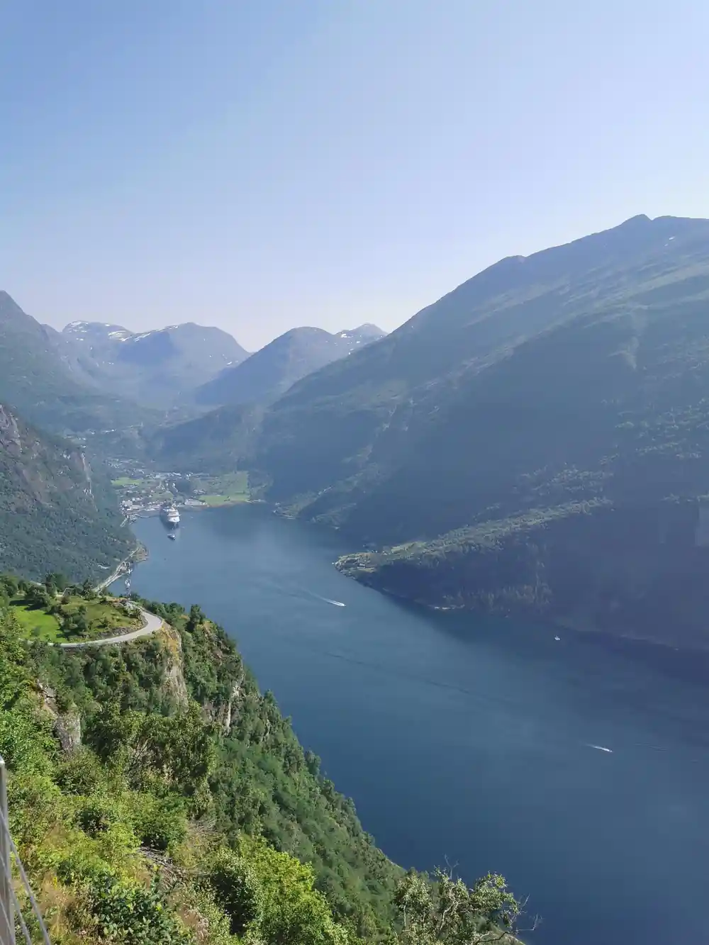Steep green mountainside descending to deep blue fjord