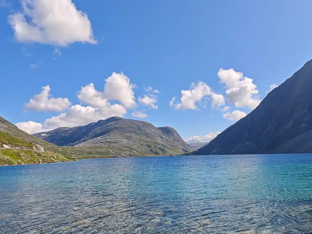 Turquoise mountain lake with rocky slopes and clear sky