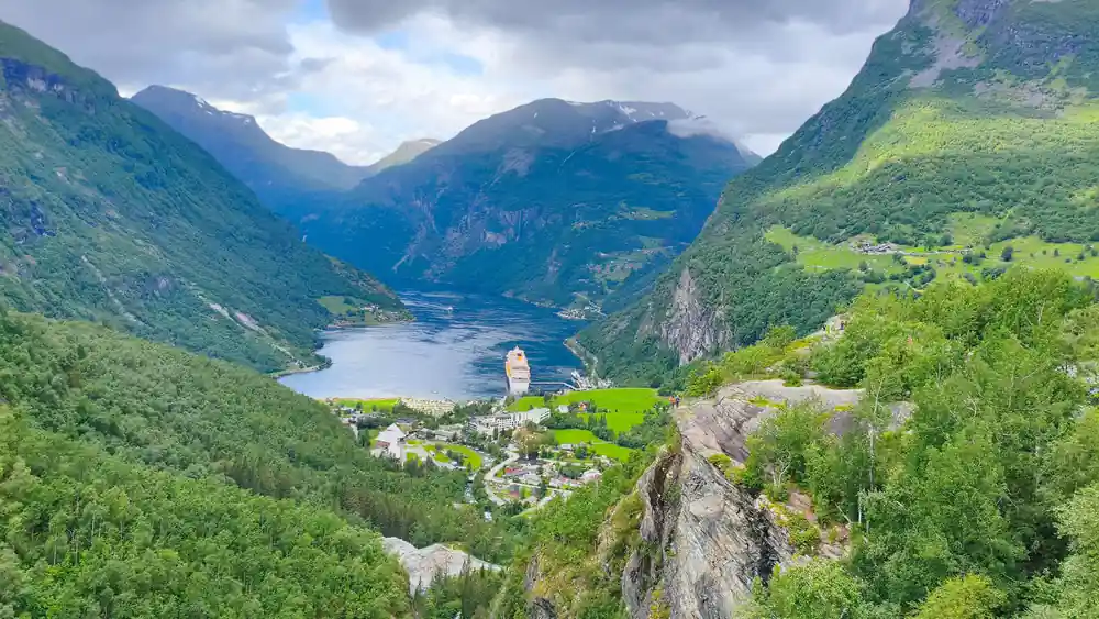 Valley with cruise ship on fjord and steep cliff faces