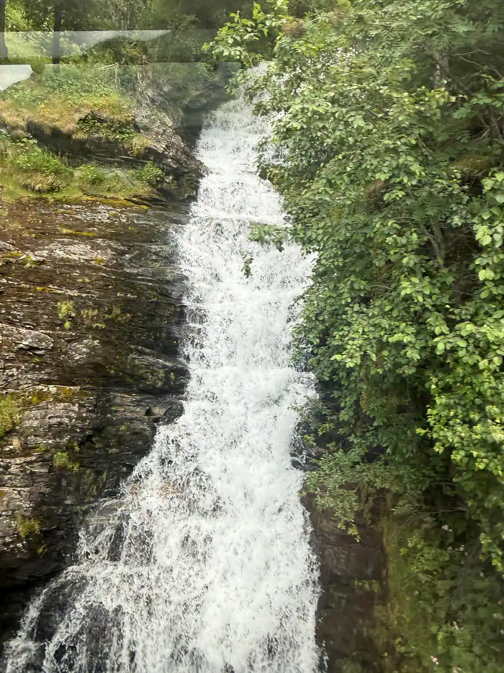 Waterfall flowing between steep rocky cliffs with vegetation